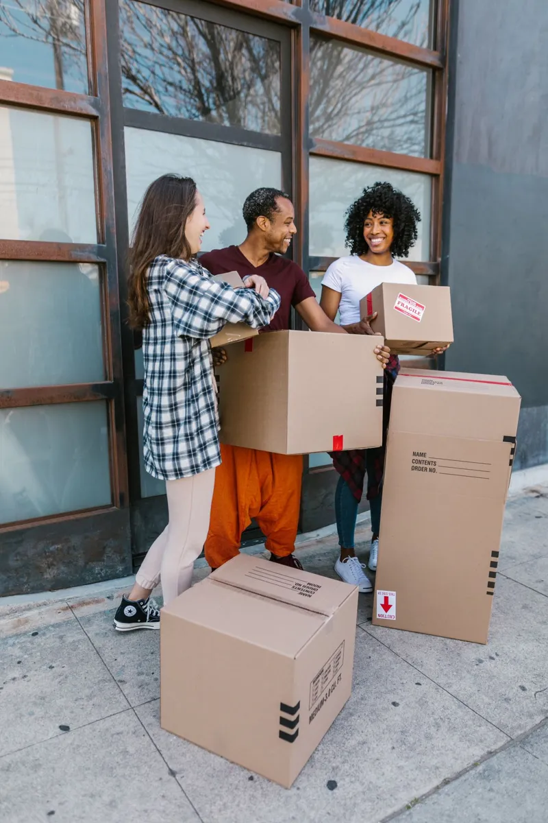 Friends carrying moving boxes together